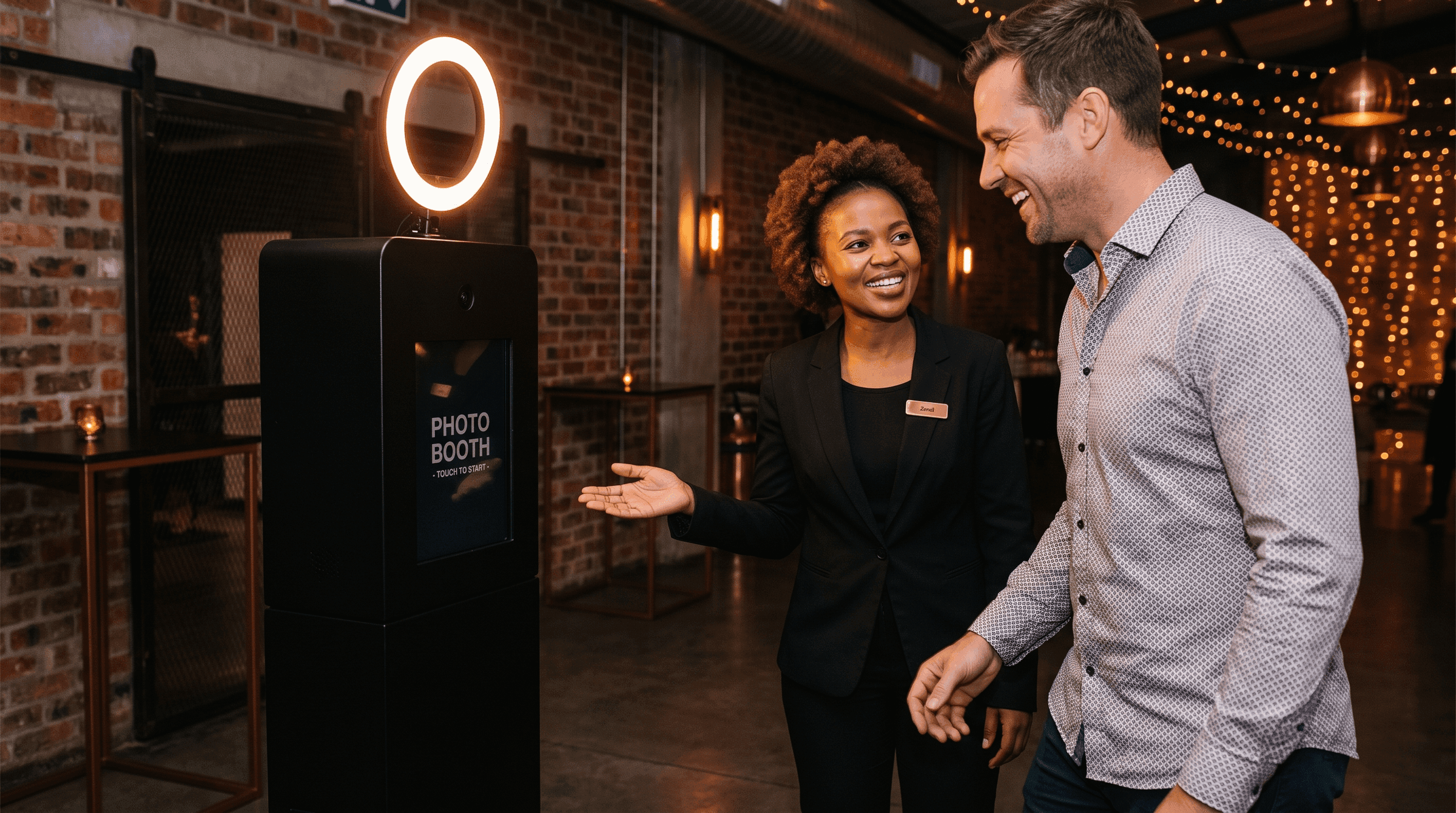 A Signal Frame host standing beside a guest at a portrait station, showing them the screen before the photograph is taken.